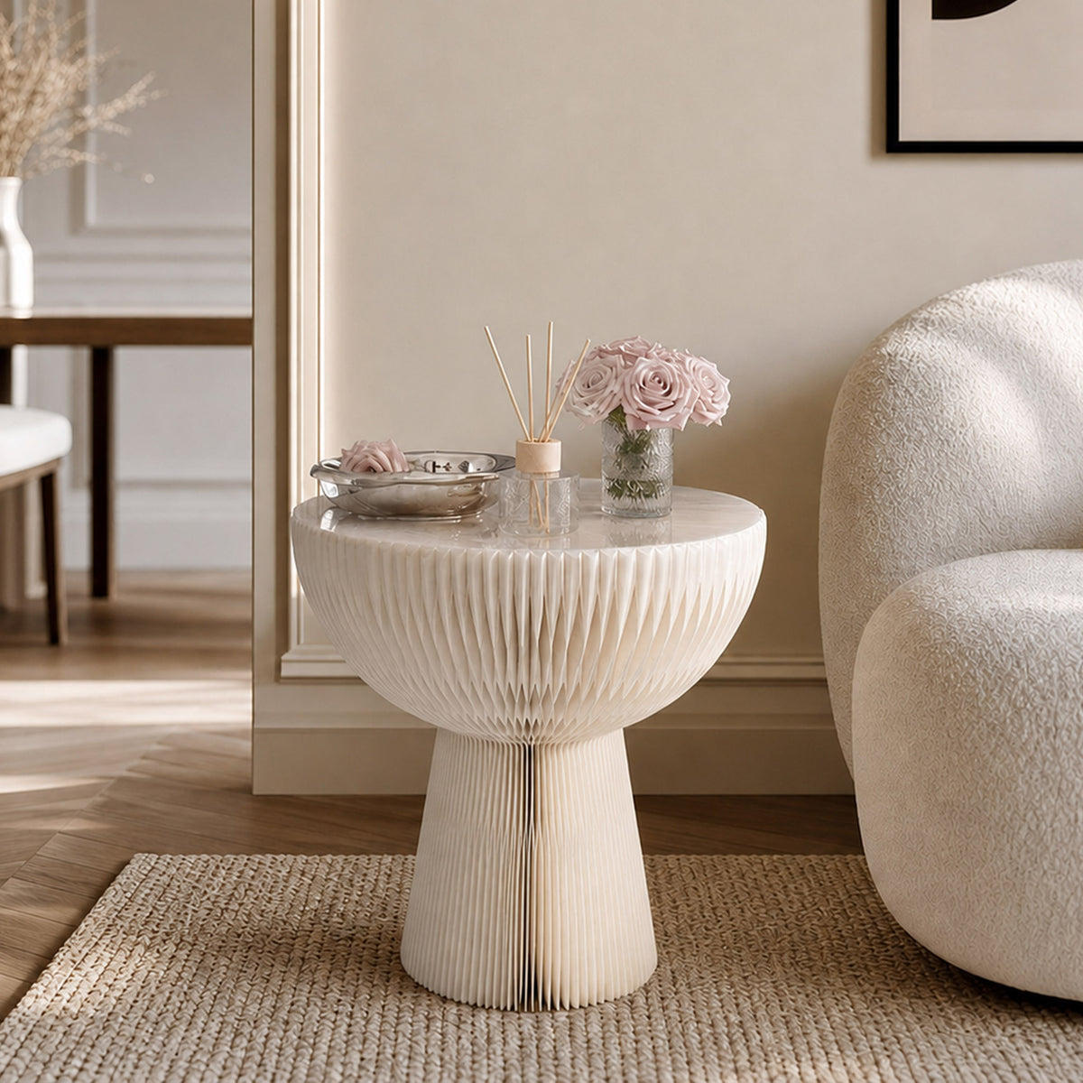 White Bouquet Side Table A styled with pink flowers and fragrance accessories beside a lounge chair.