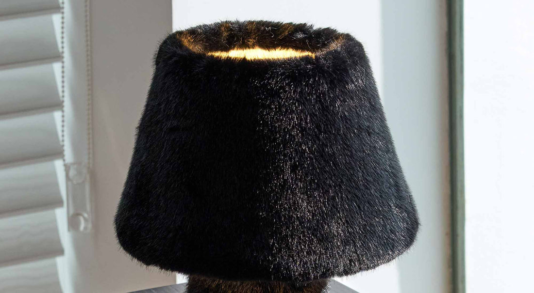 The ARTAMORE faux fur table lamp serving as a quiet, comforting companion on a warm minimalist bedside table.
