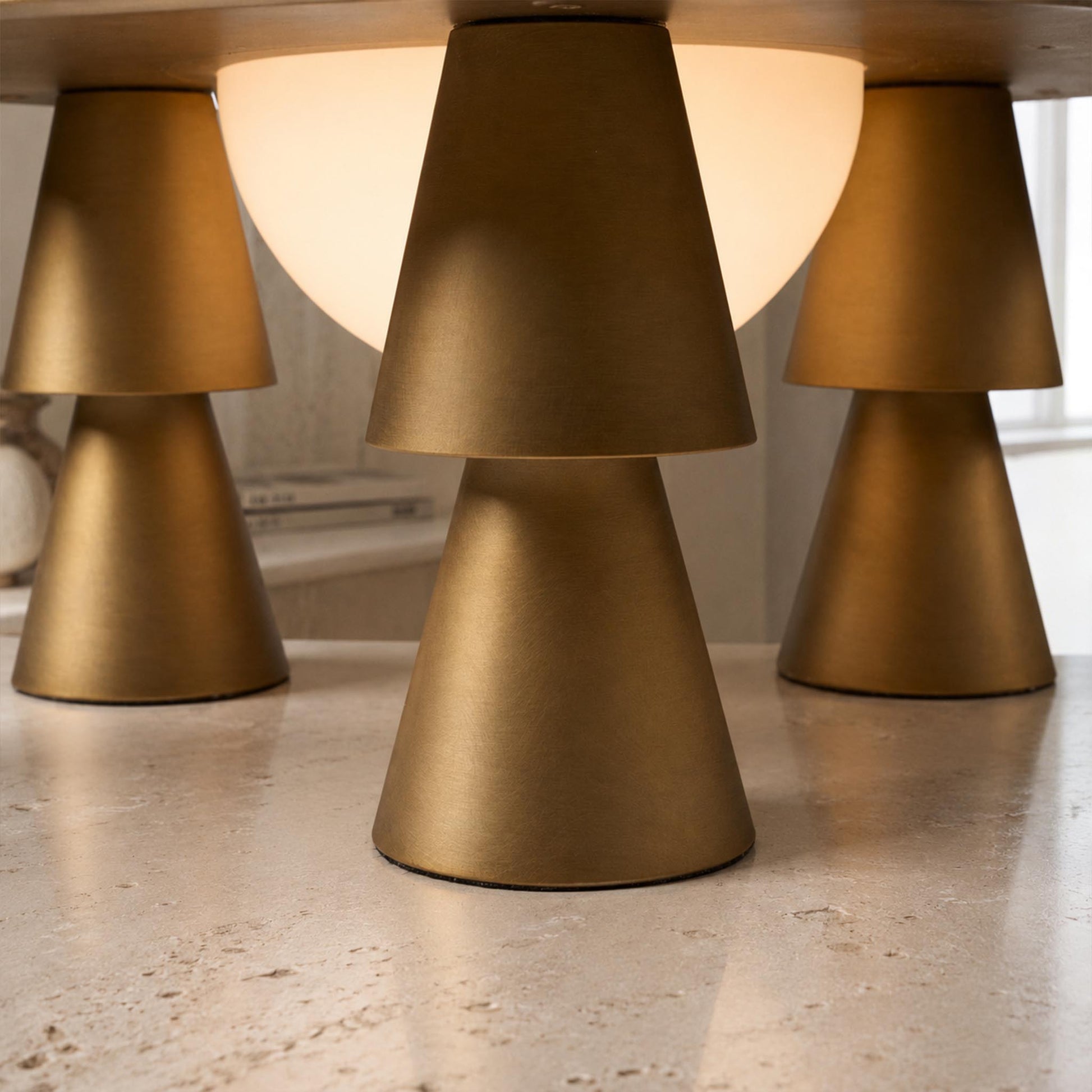 Close-up of the gold conical legs and frosted glass diffuser on the Metal Creative Table Lamp.