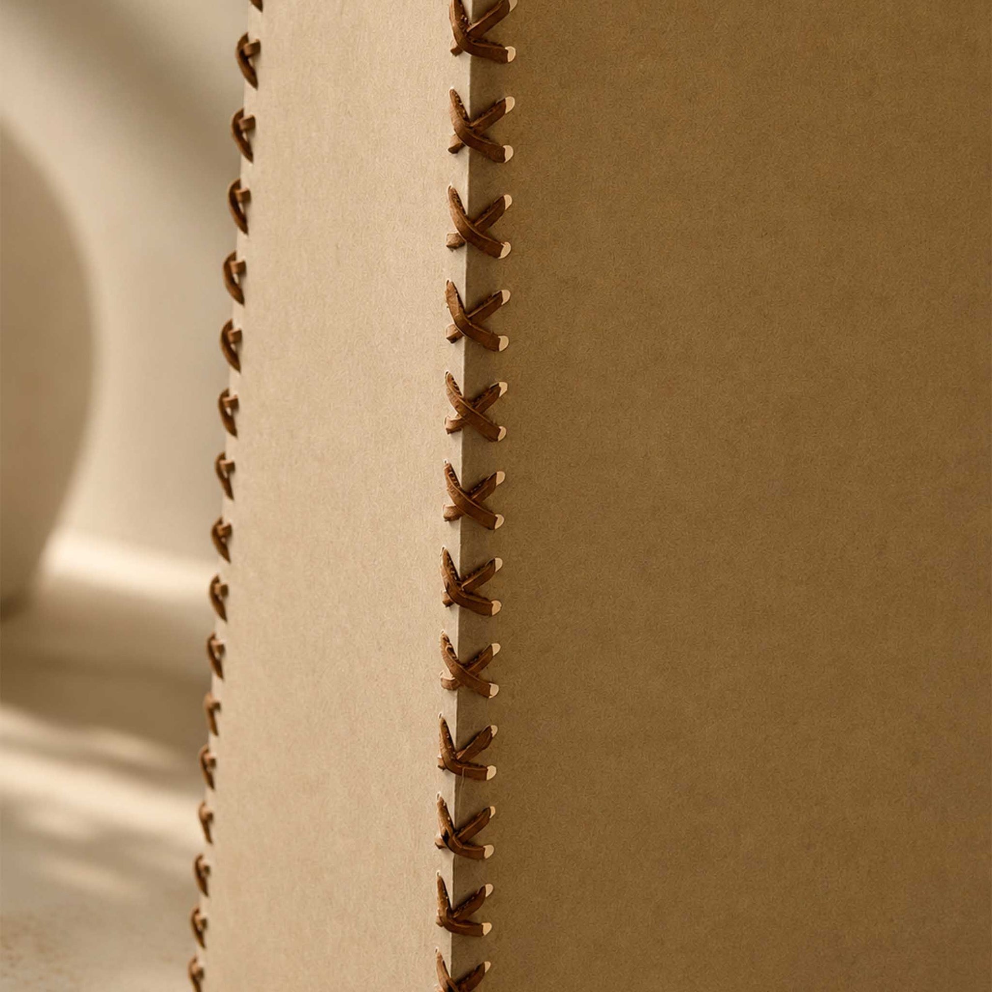 Detailed view of the Handmade Parchment Letter Lamp shade with leather cord stitching and soft ambient light.