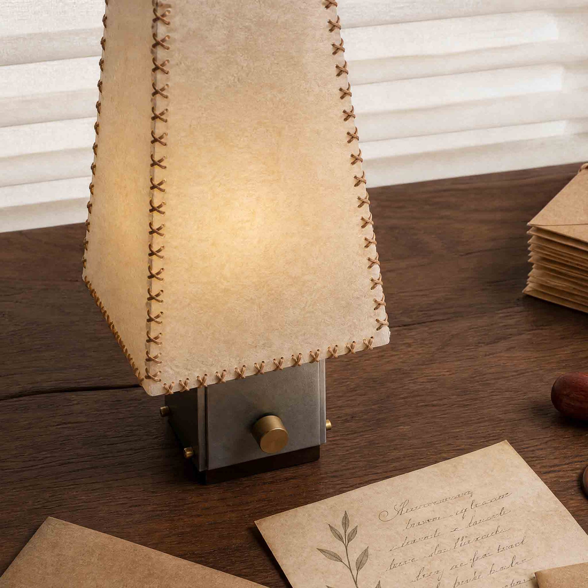 Close-up of the parchment lampshade with hand-stitched leather cord edging and warm translucent texture.