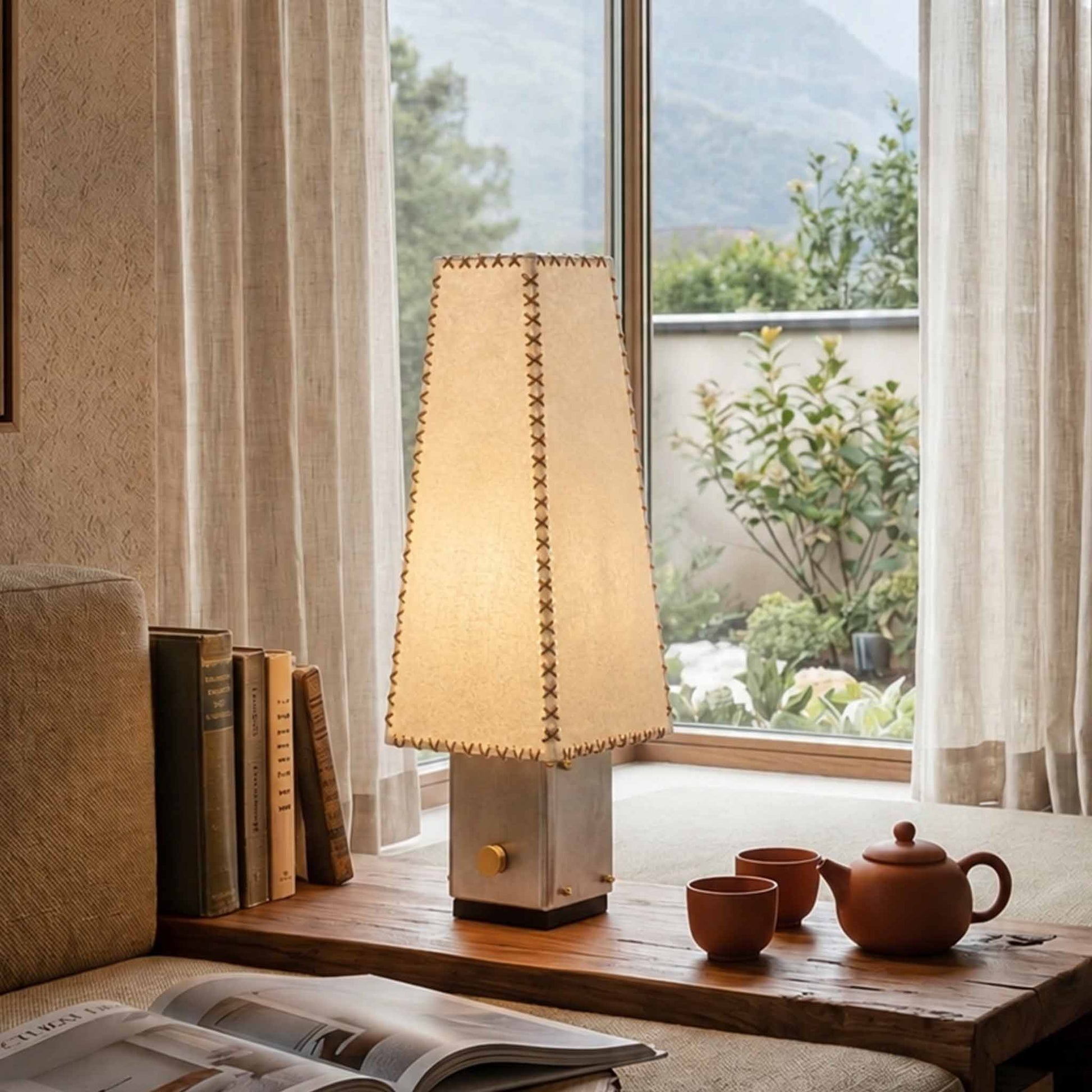 Handmade Parchment Letter Lamp glowing on a wooden window bench with books, tea set, linen curtains, and mountain view.