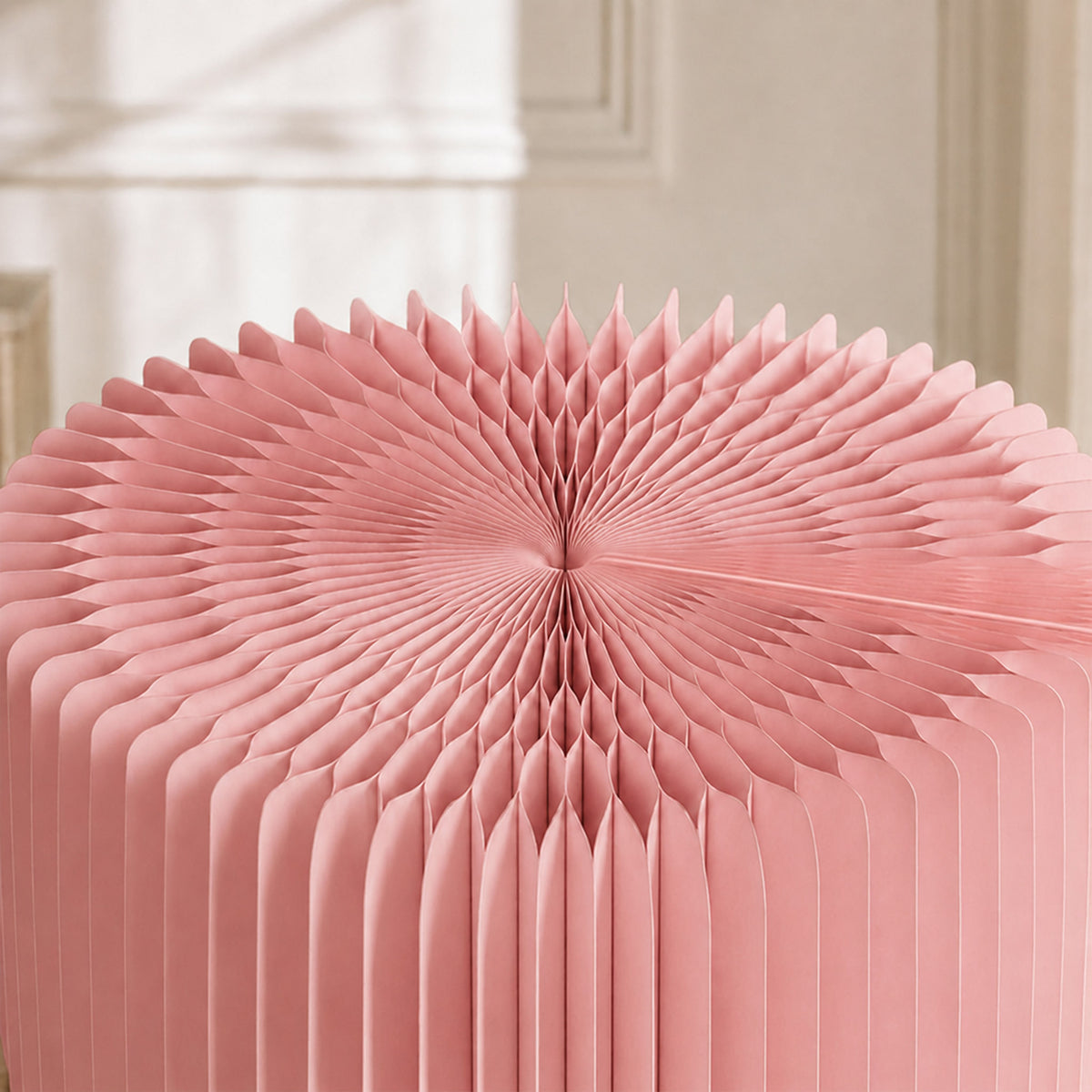 Close-up of the pink LOTUS Stool B revealing the expandable honeycomb paper cells and foldable construction