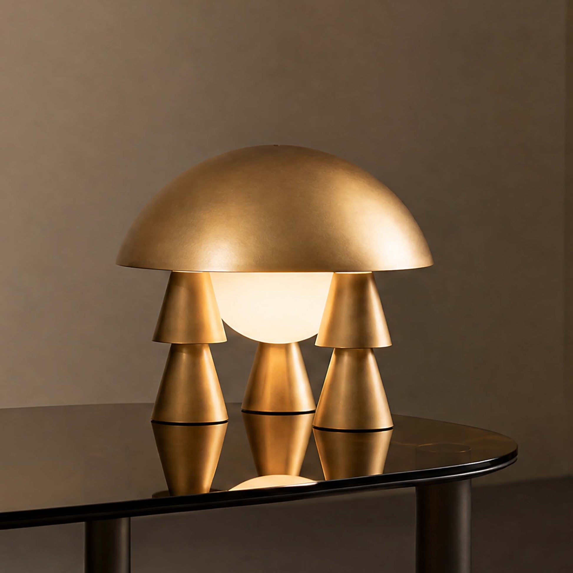 Metal Creative Table Lamp with a gold sculptural form and soft light reflected on a dark glass table.