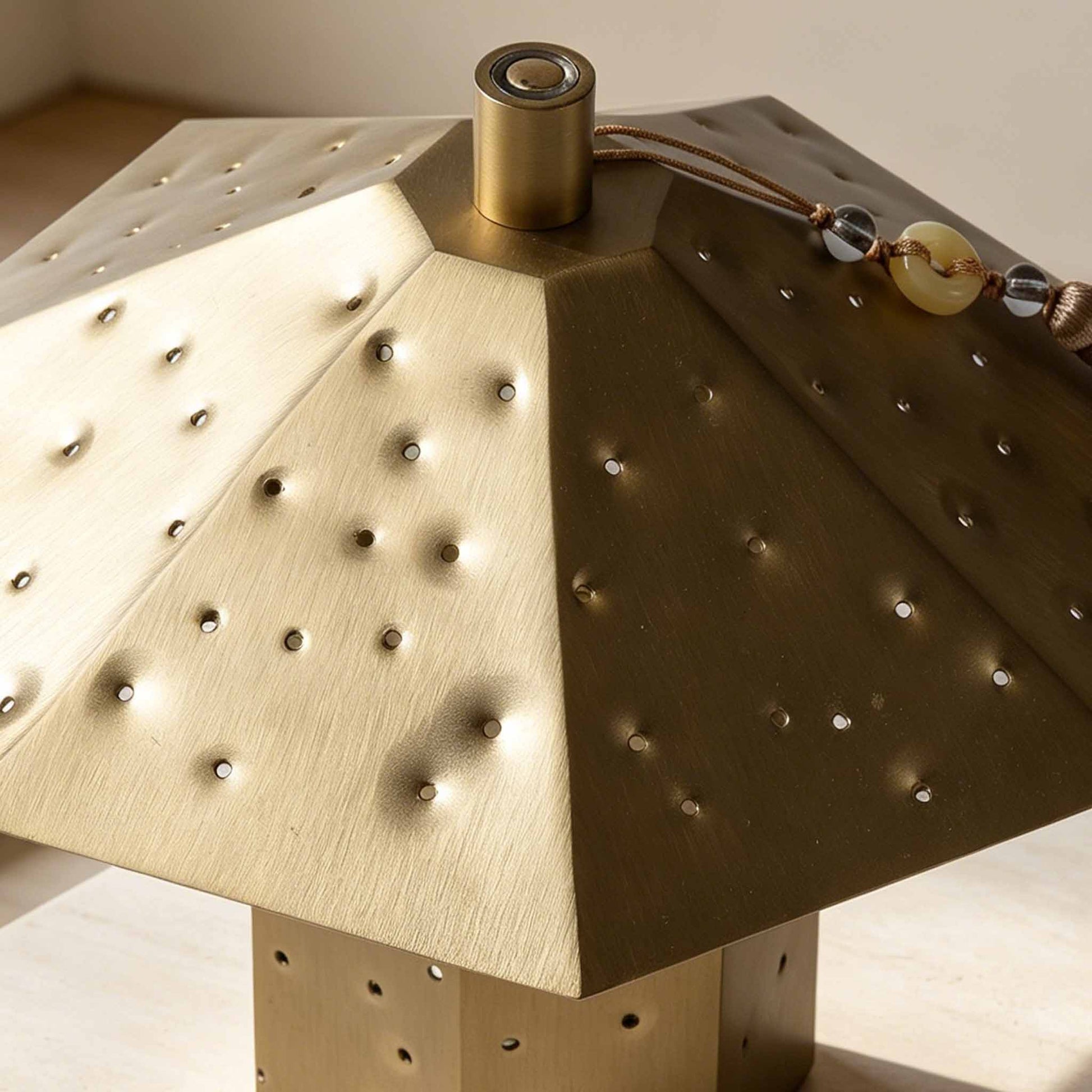 Close-up of the perforated metal shade on the Polyhedron Starry Night Light with warm light points.