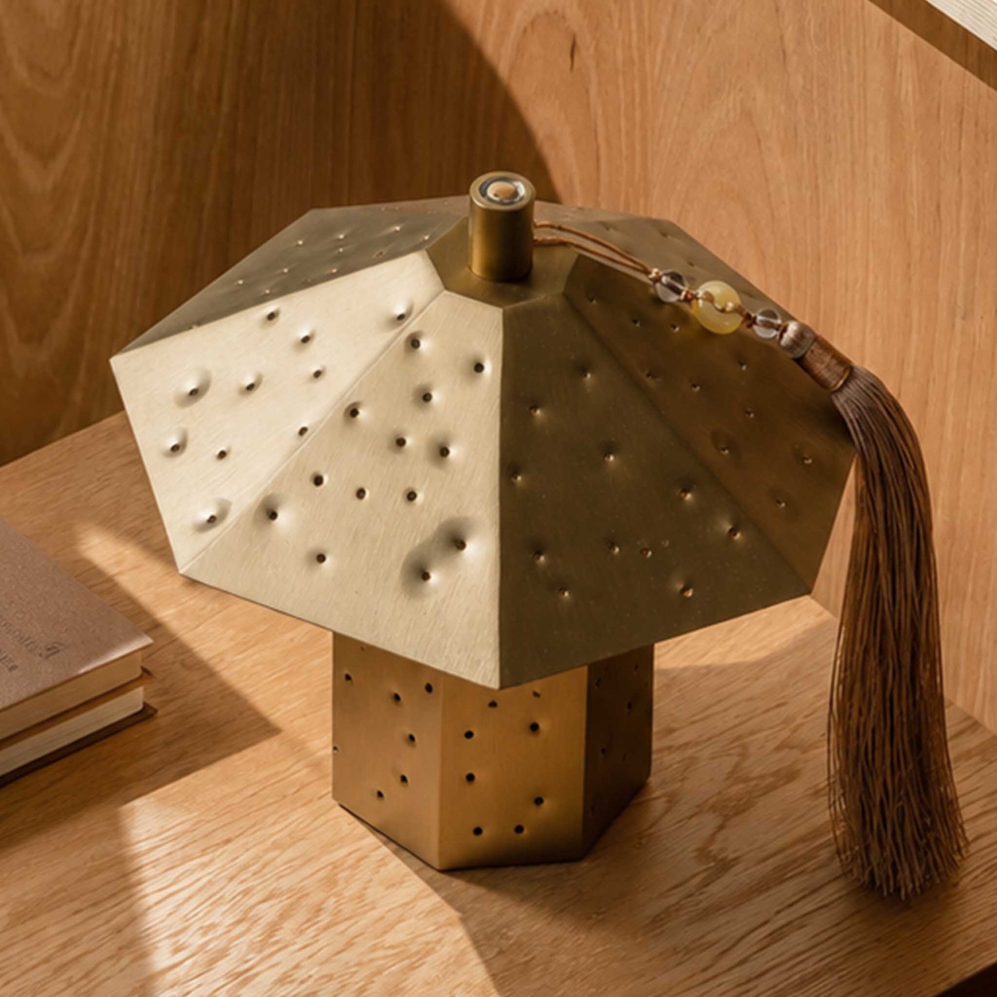 Close-up of the brushed metal polyhedron night light with hammered perforations and tassel detail.