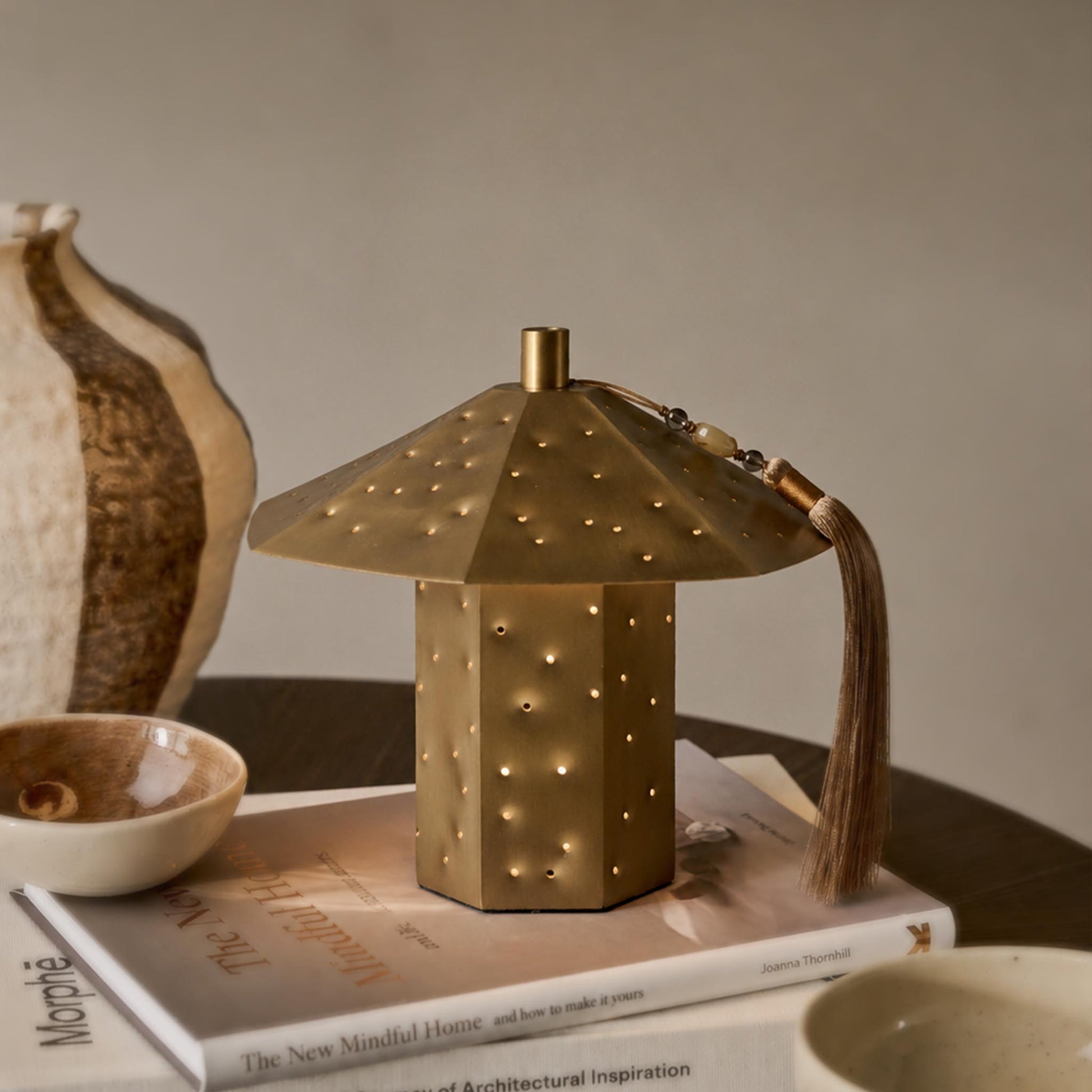 Gold-tone polyhedron starry night light with perforated metal shade and tassel on a styled tabletop.