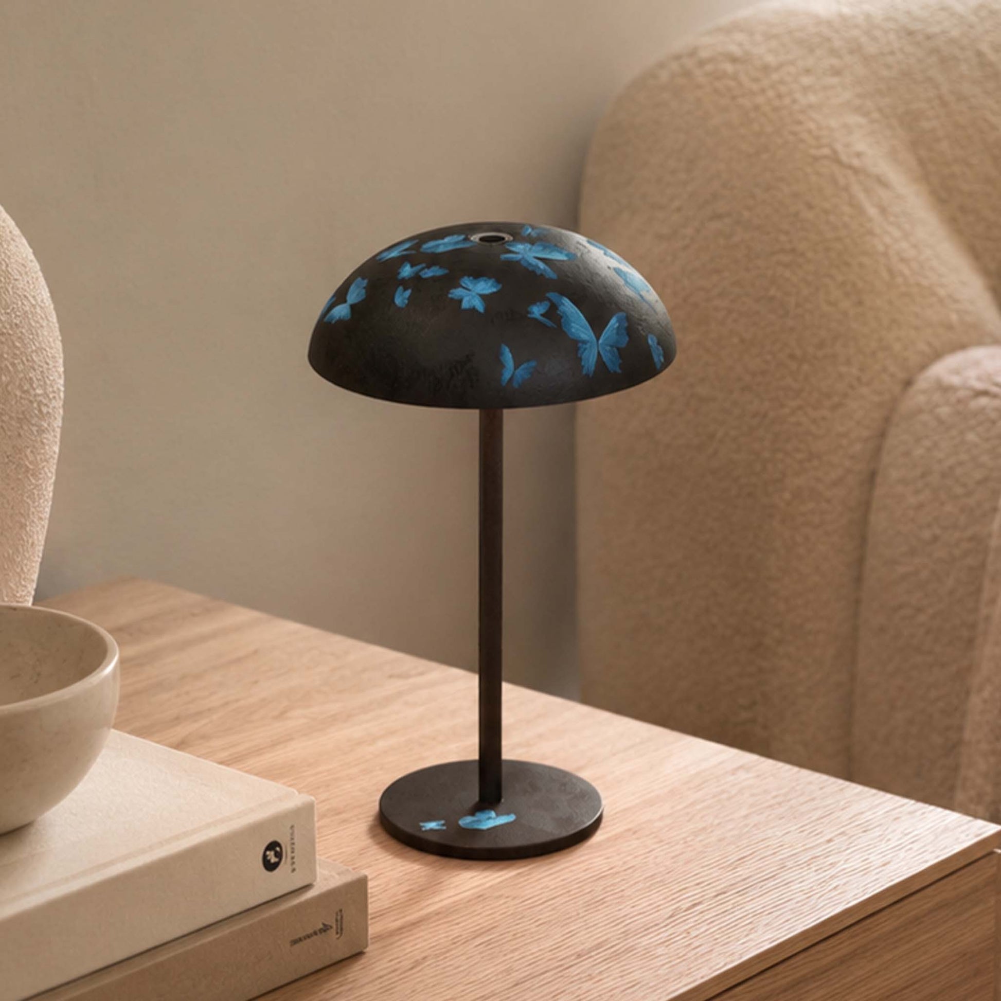 Dark gray Relax-W table lamp with blue butterfly artwork on a wooden side table in a cozy modern interior.