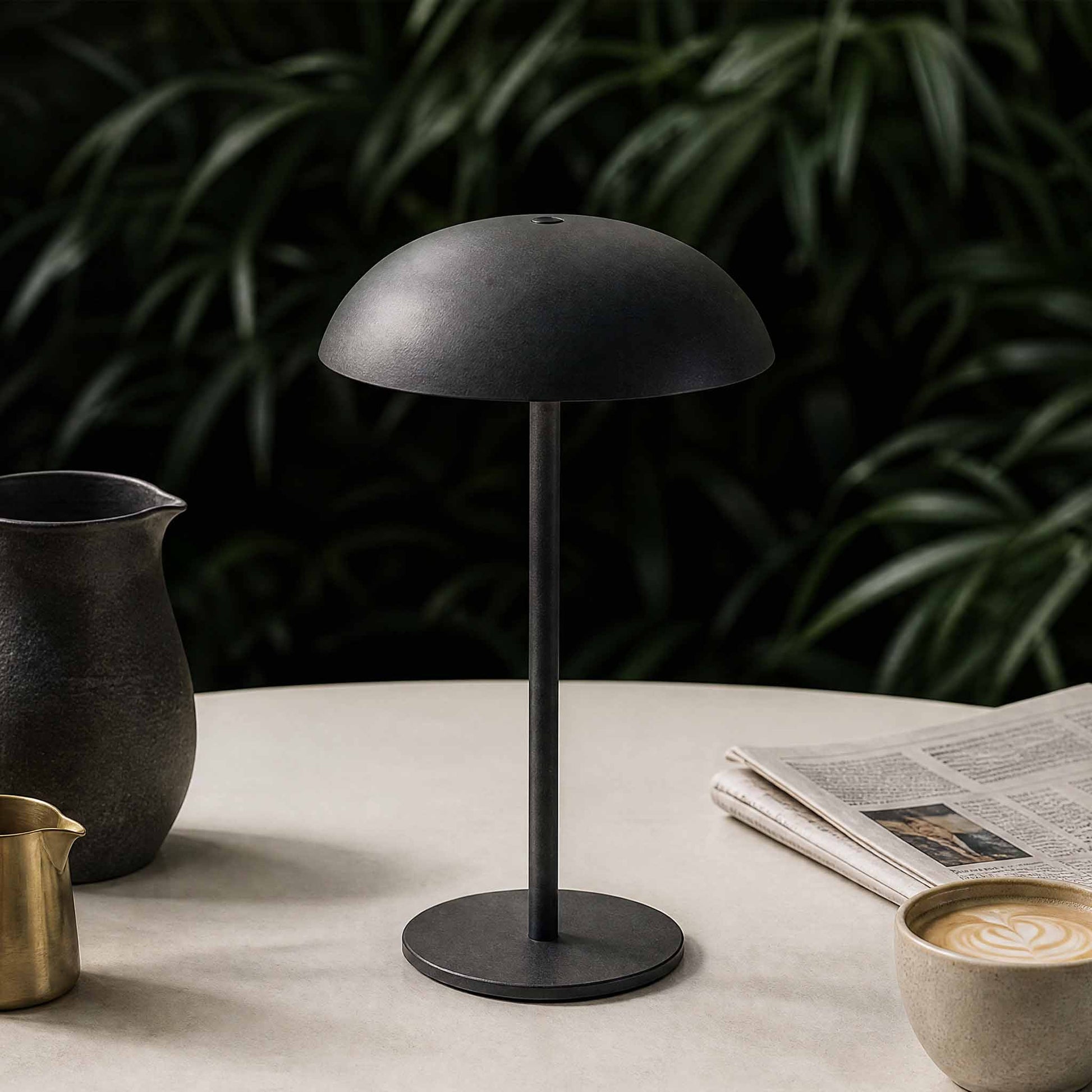 Dark gray portable Relax-W table lamp on a tabletop with coffee and newspaper for modern home decor.