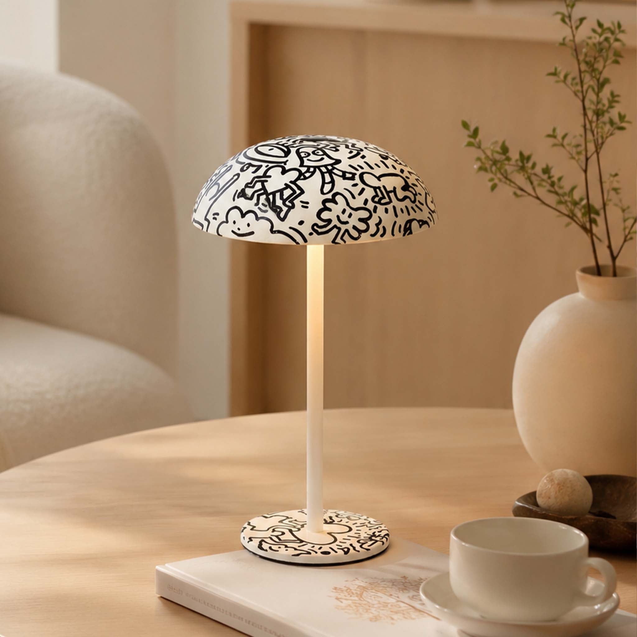 Black and white doodle painted table lamp with warm light on a coffee table in a cozy modern interior.