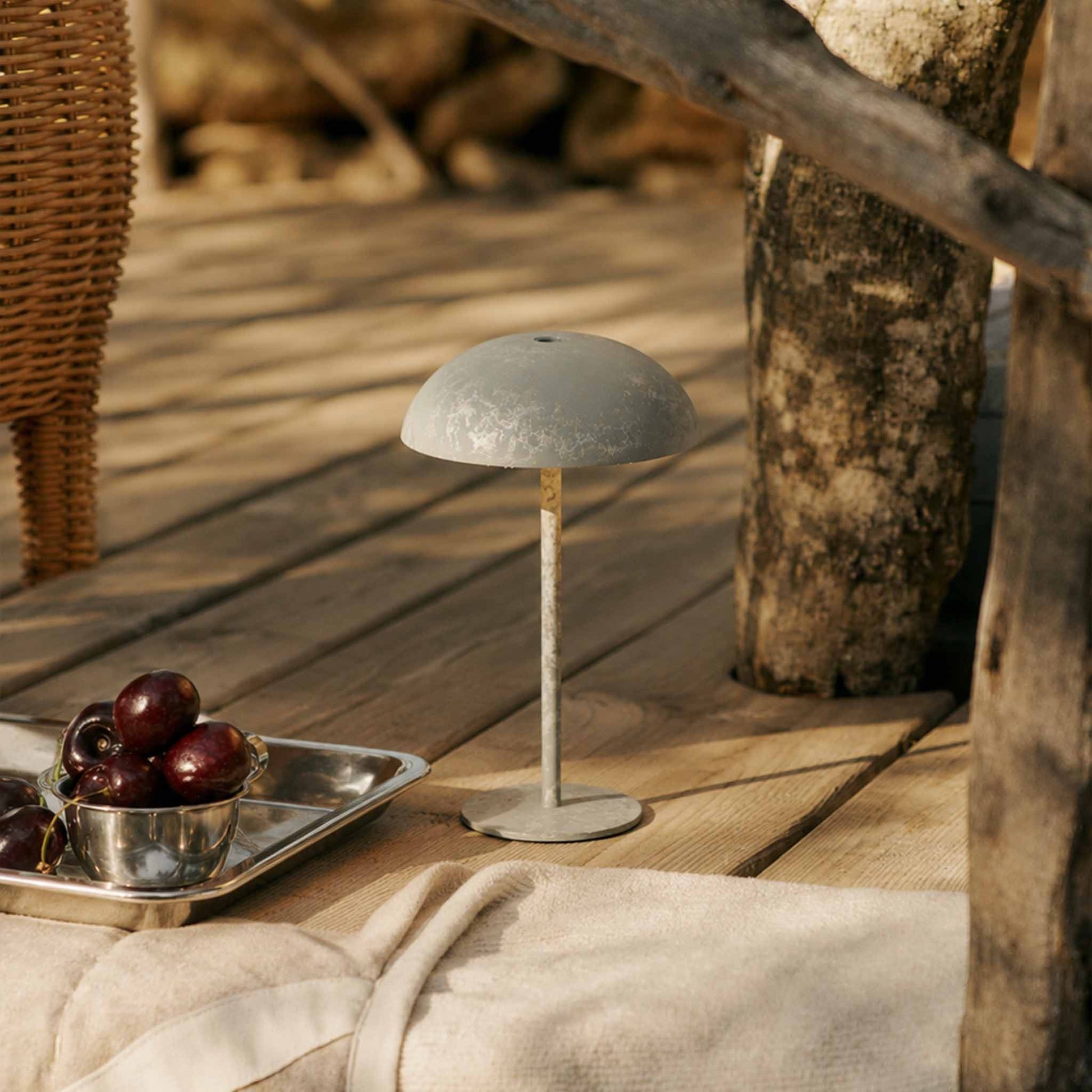 White portable table lamp with a micro-cement finish on a wooden outdoor deck for patio and picnic lighting.