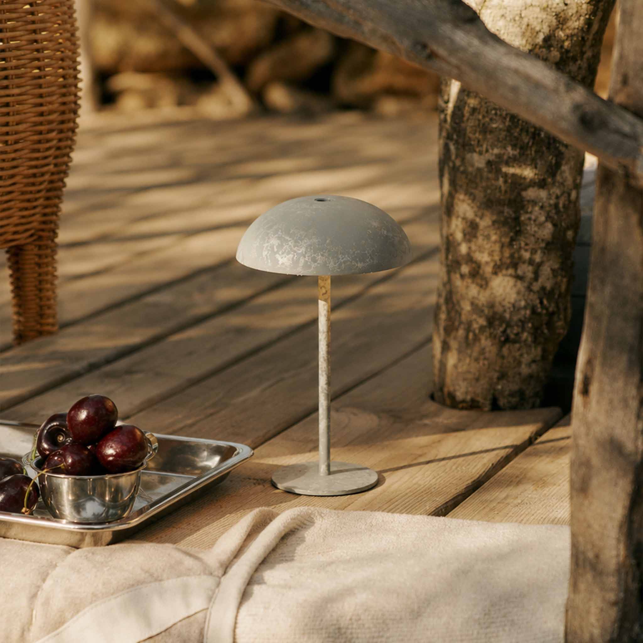 White portable table lamp with a micro-cement finish on a wooden outdoor deck for patio and picnic lighting.