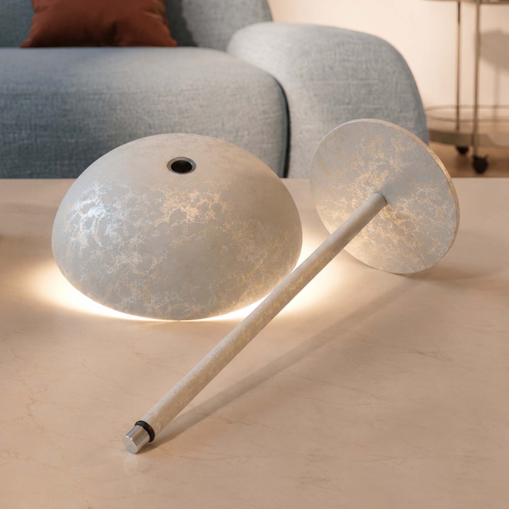 Disassembled Relax-W table lamp showing the dome shade, slim pole, round base, and warm ambient light.