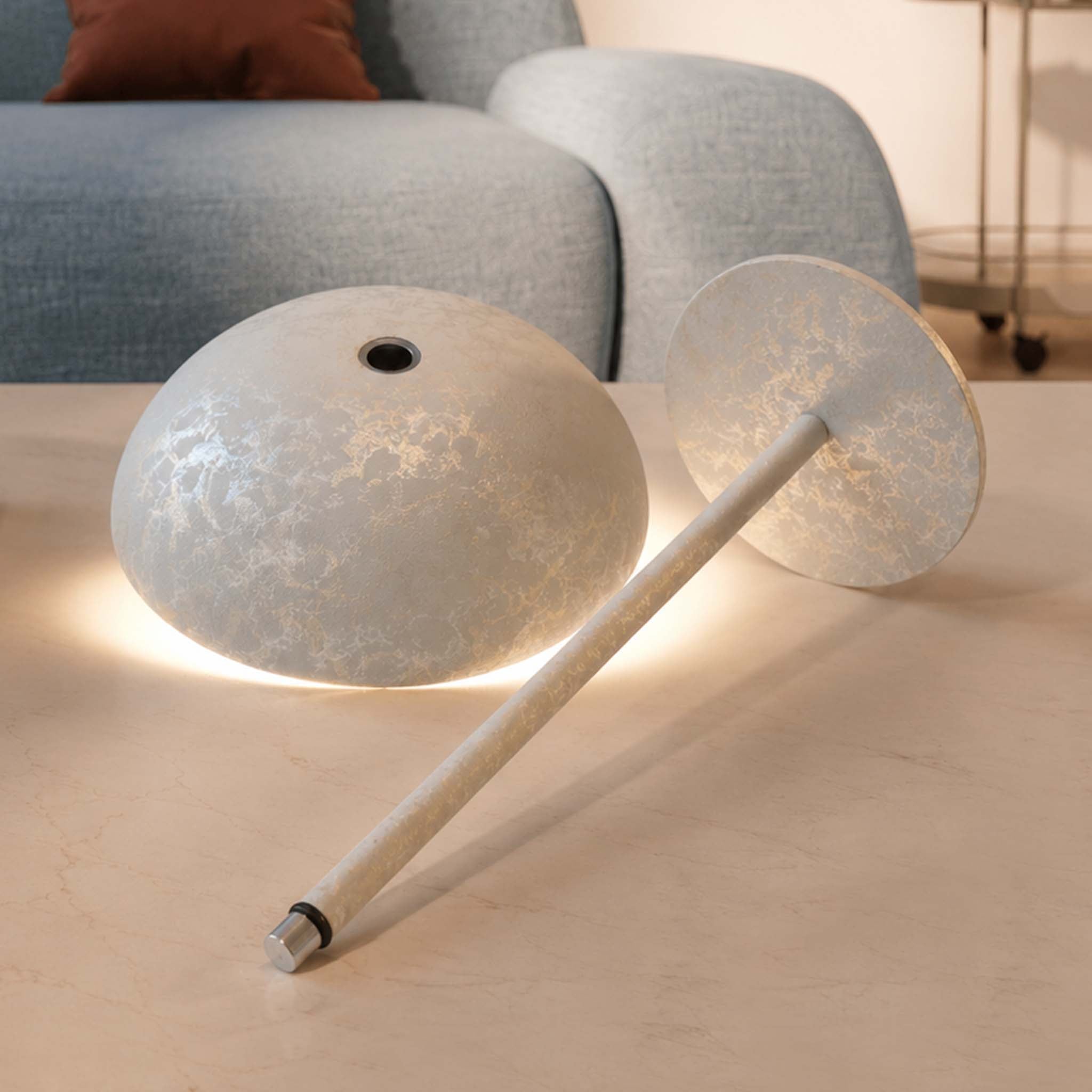 Disassembled Relax-W table lamp showing the dome shade, slim pole, round base, and warm ambient light.