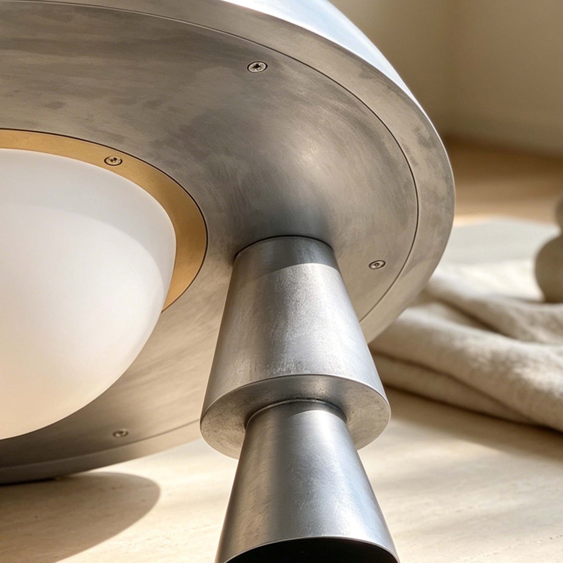 Close-up of the silver aged aluminium table lamp showing the conical leg, dome shade underside, and frosted glass.