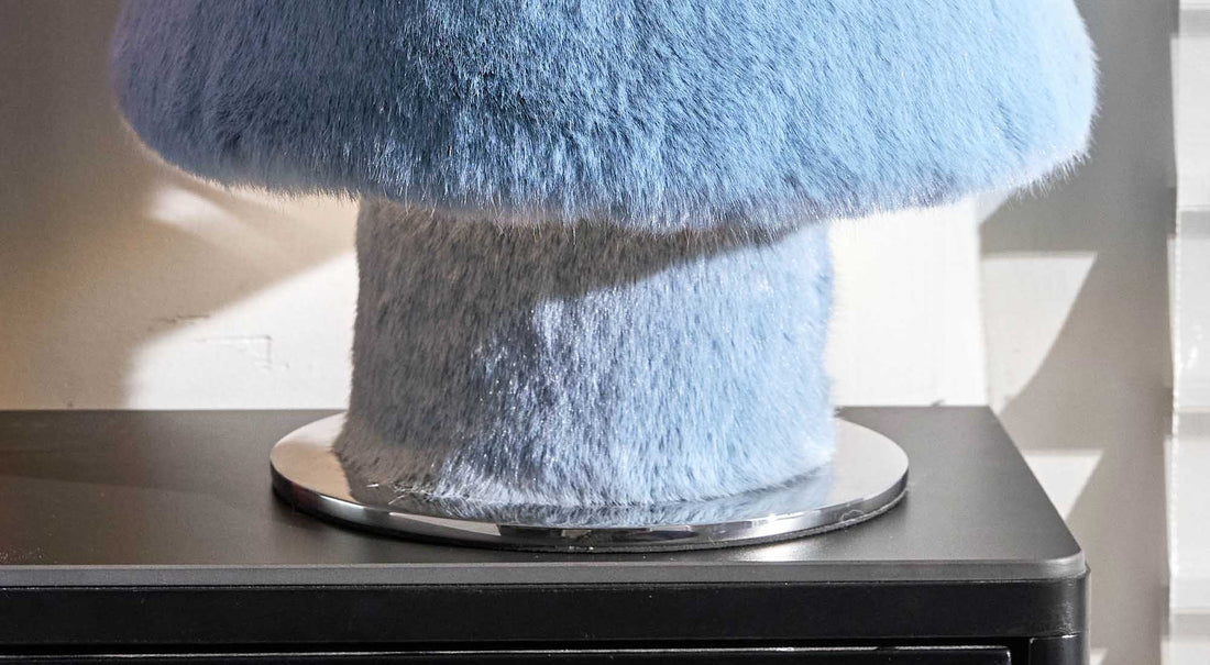 Soft beams of light gently filtering through the plush fur fibers of the ARTAMORE table lamp, creating a warm embrace.